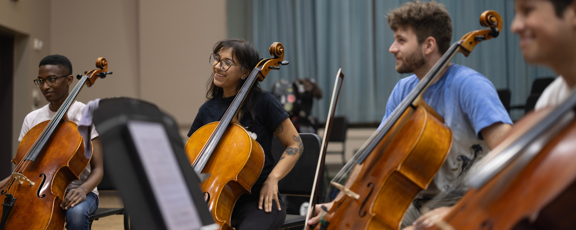 Several cellists smiling in a sectional