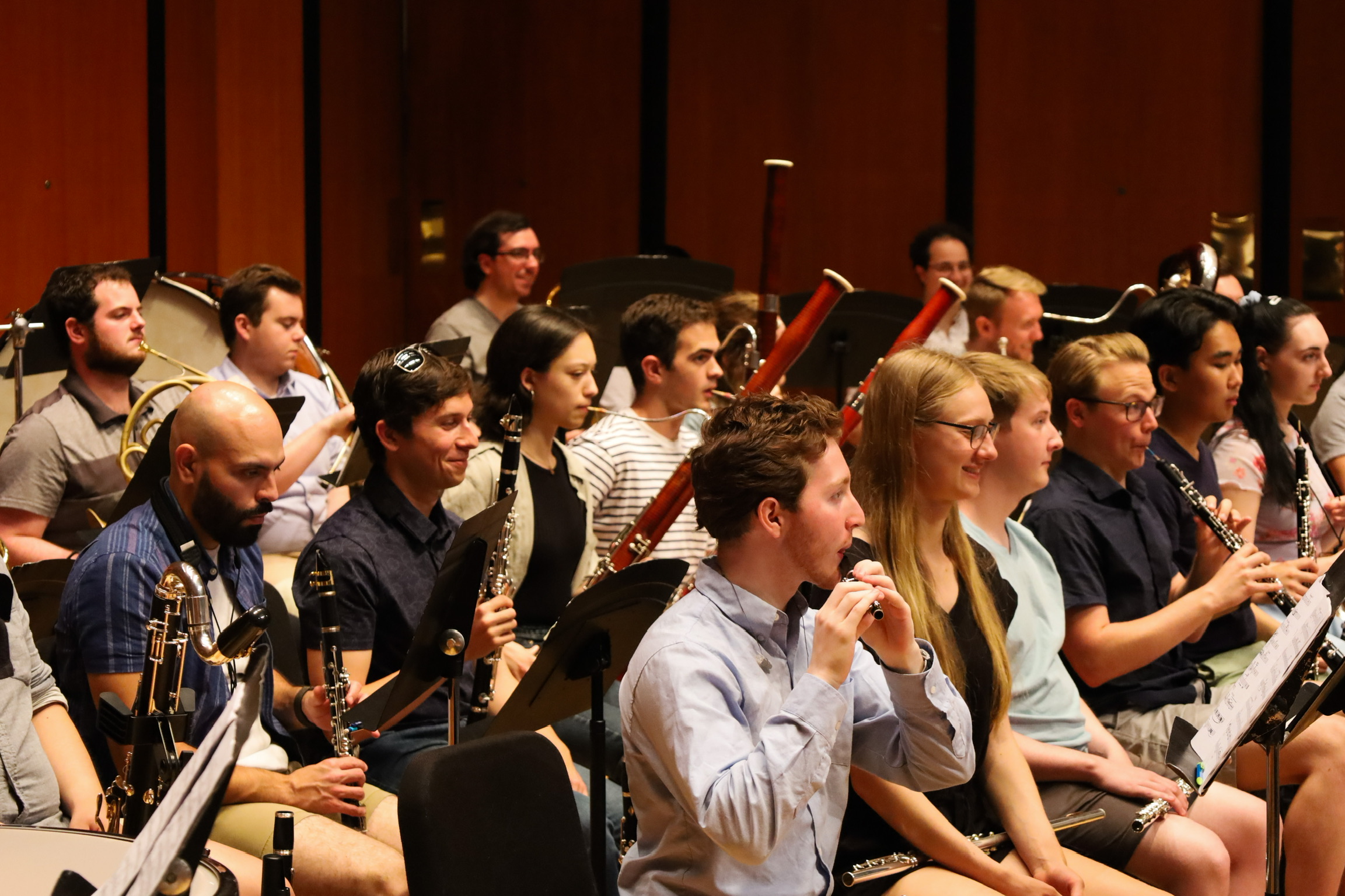 woodwind and brass orchestral rehearsal. Piccolo, oboe, and bassoon play while the rest of the instrumentalists are happily looking at their music.