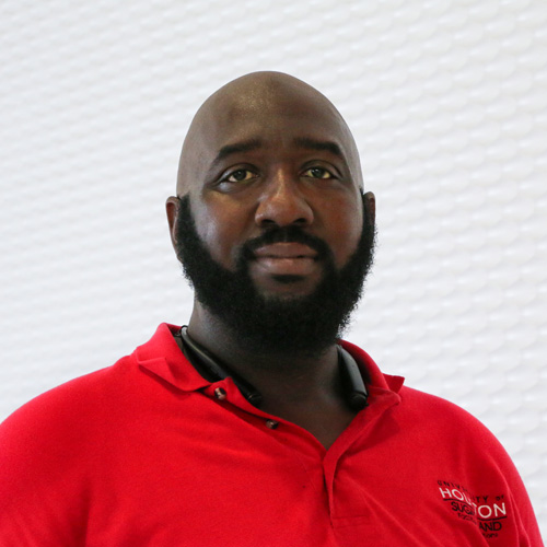 Portrait of a bald black man with a Garibaldi beard wearing a red polo shirt