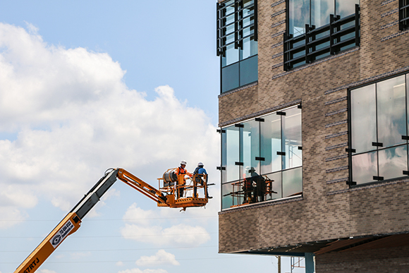 An articulated lift carrying constructions workers to an exterior window