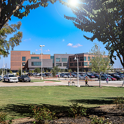 Photo of a brown three story building framed by two trees